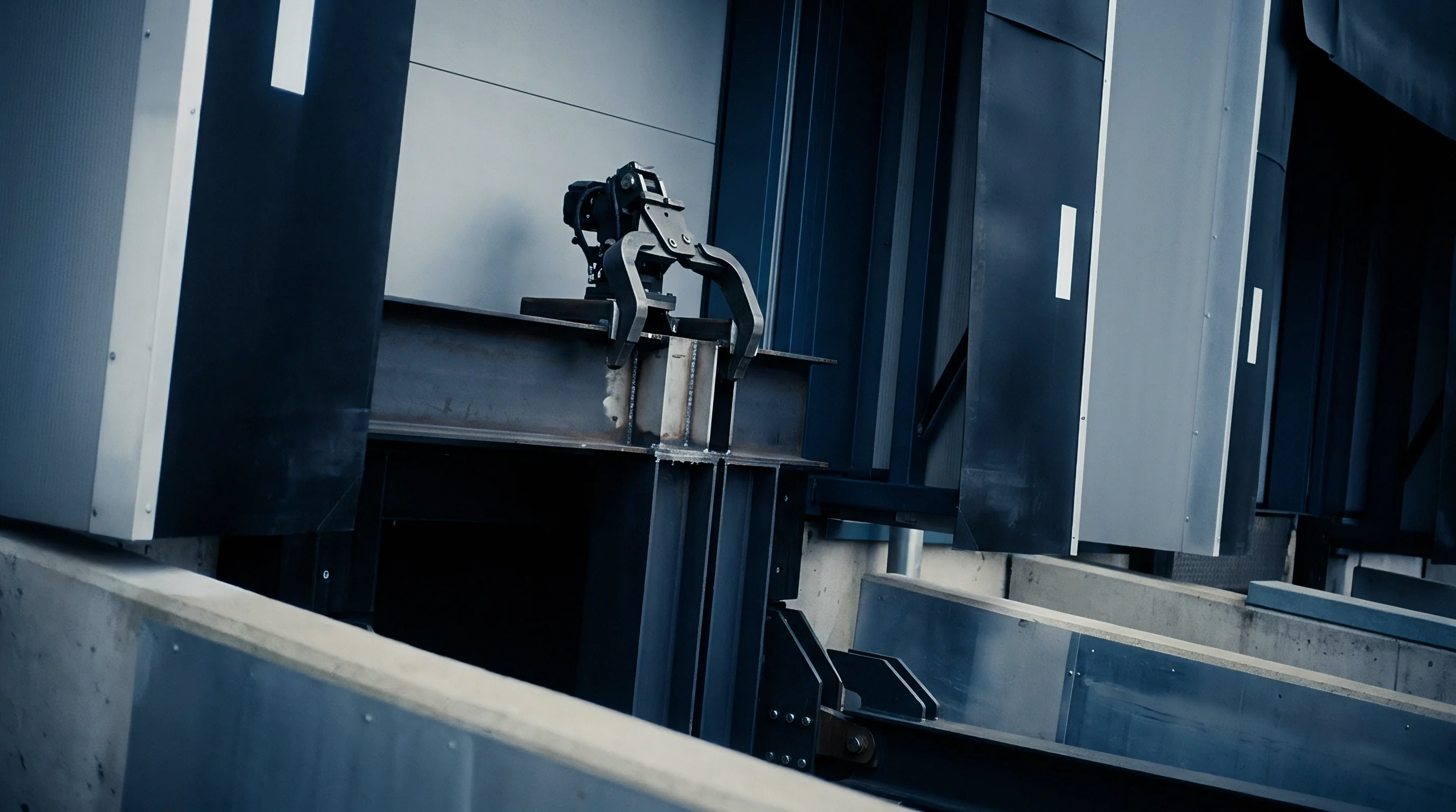 Automated robotic clamping mechanism positions heavy structural steel beams inside an industrial manufacturing facility during assembly operations.